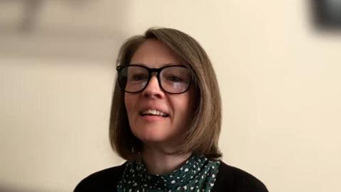 Eilidh NicFhionghain, na suidhe air beulaibh chamera agus gàire air a h-aodann