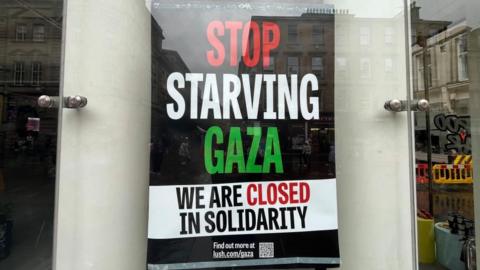 A post in a window reading: Stop starving Gaza, we are closed in solidarity 