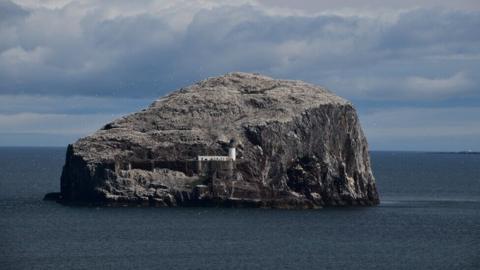 a rocky island with a lighthouse in the middle of the open sea