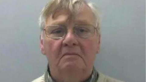 Police mugshot of former Sunday School teacher John Laister, wearing a green shirt, white jumper and glasses. He is already serving a sentence for raping and sexually abusing young girls under his care in West Yorkshire