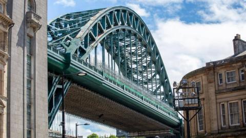 Restored section of the Tyne Bridge showing scaffolding and the structure's heavily riveted lower west arch, freshly painted in the shade Hollybush Green.
