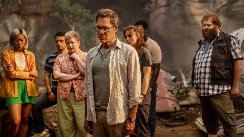 Nine Bodies in a Mexican Morgue - Episode 1 artwork. 
Plane survivors stood around, collectively looking at something on the ground