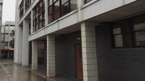 Exterior shot of the tiled, grey court building in Runcorn on a rainy day