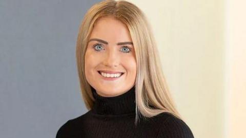 Picture of Simone White smiling at the camera in black top with blonde hair