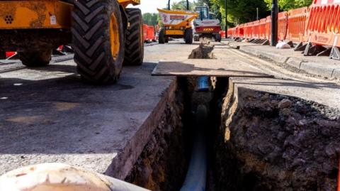An exposed water main pipe on a road