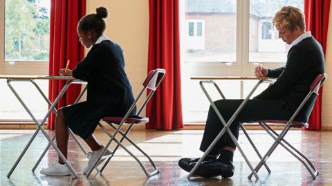 GCSE maths image: an exam hall with teenage students taking exams, concentrating.