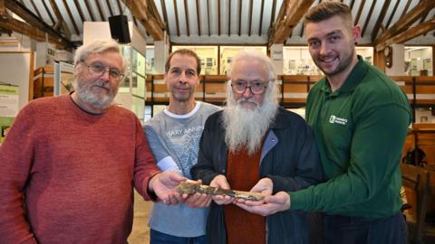 Four men cradling the fossilised bone inside a museum