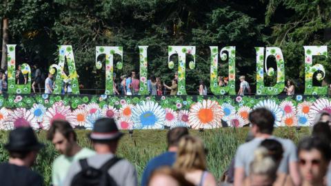The famous flora Latitude Festival sign, In the foreground there are people with blurred faced.