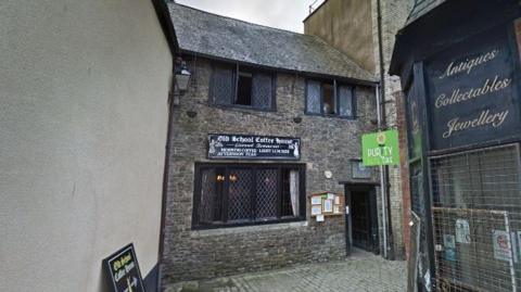 A building with exposed brick and lattice windows. The sign above its main window reads 'Old School Coffee House'.  