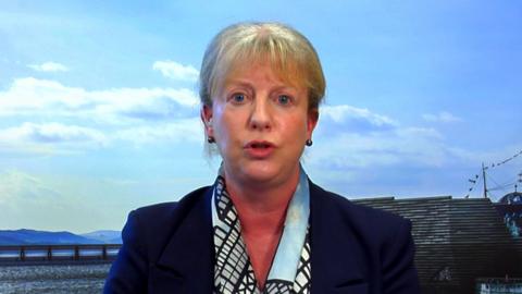 Scottish Finance Secretary Shona Robison sitting in front of a backdrop showing Dundee and the Tay Bridge.