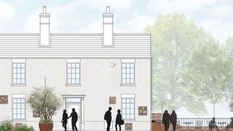 An artist's impression of the proposed cafe. It is a two-storey end of terrace house with a large chimney. Next to it is a seating area with tables and chairs and the River Slea behind it 