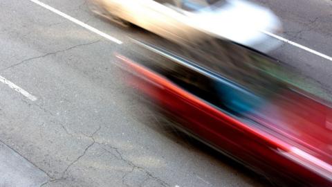 A motion blurred image of a red and white car driving on a road.