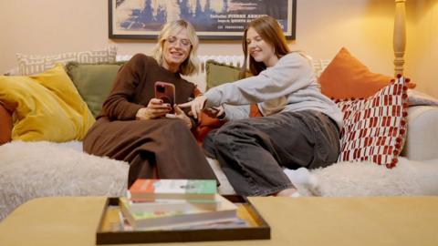 Zoe Ball and her daughter Nell look at a phone while sitting on a sofa together