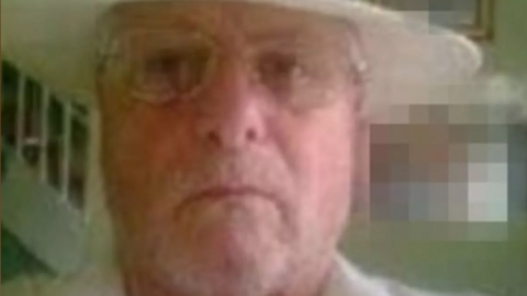 Blurry selfie taken by Smith. He wears a cream panama hat and white top. He has clear glasses and a grey beard.
