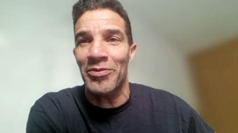 David James has short dark hair and is wearing a navy blue jumper.
