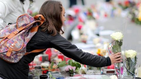 A women lights a candle on the monument of the 'Place de la Republique' where people continue to pay tribute to the Paris attack victims