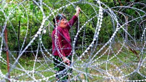 Woman next to razor wire on South Ossetia border, Khurvaleti, 25 Jul 13