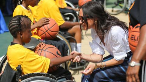 Meghan shakes hands with a wheelchair basketball player, as she attends a basketball event in Lagos, Nigeria