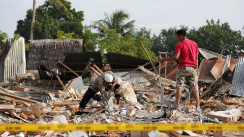 Men look for items to salvage from a building which collapsed in Pidie Jaya, Aceh province, Indonesia December 10, 2016