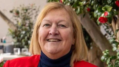 Dame Julie Kenny in a red jacket