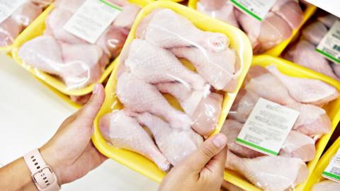 Hands holding a packet of raw chicken meat