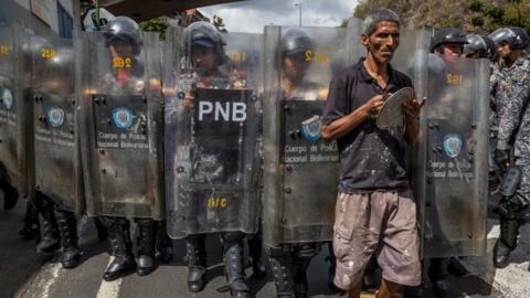 A man protests in front of members of the Bolivarian National Police (PNB) in Caracas, Venezuela, 28 December 2017