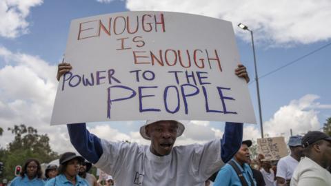 A man holds up a sign in protest against the power outages