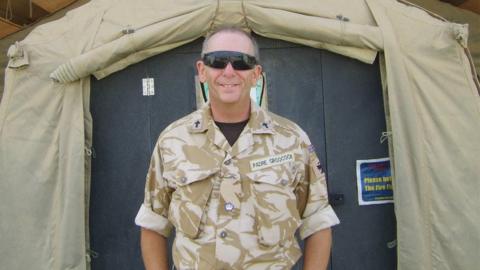 Chris Groocock when he was a padre in the British Army standing in front of a tent which was the church in Camp Bastion 2