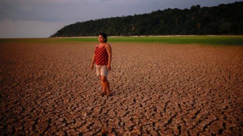 Woman stands on parched river bed in the Amazon rainforest