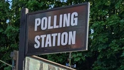 A pub called Larkins Bar, with a black and white polling station sign and signs directing voters on where to go.