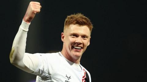 Sam Clucas holds up his right arm and makes a fist in celebration at scoring for Lincoln City