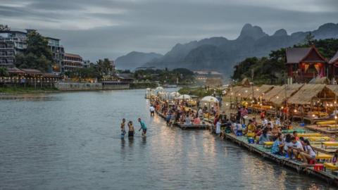 Wideview of a river in Vang Vieng showing people along the river front