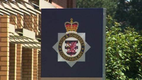 A sign with the 'Avon and Somerset Constabulary' logo on. The sign is connected to a brick building. 