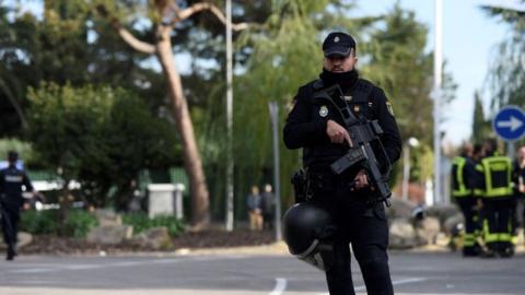 A Spanish policeman helps to secure the area after a letter bomb explosion at the Ukrainian embassy in Madrid on Wednesday