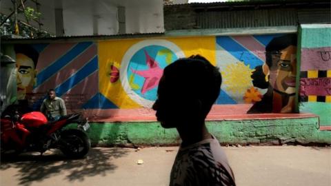 Indian commuters walk past a painted wall at Sonagachi red light district in Kolkata