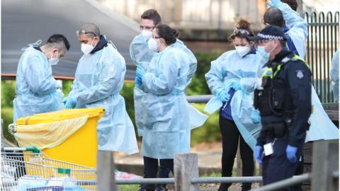 Medical workers and police are seen at a Government Commission tower which remains under strict lockdown in Melbourne, Australia, 18 July 2020