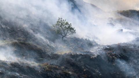 An area of moorland hillside thicky covered in smoke from burning vegetation
