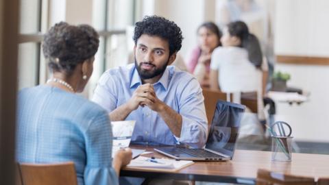 Mature female bank customer discusses opening a savings account with a bank employee