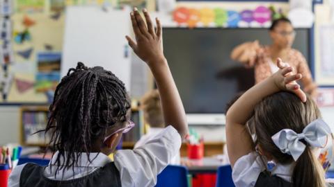 Children raising hands in class