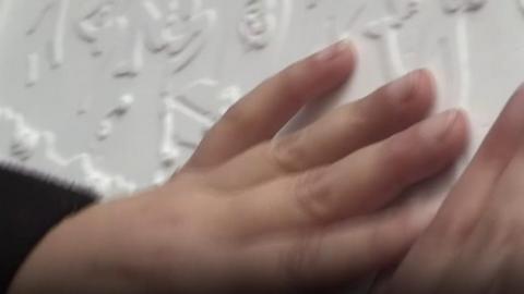 Blind woman's hand touches tactile art work