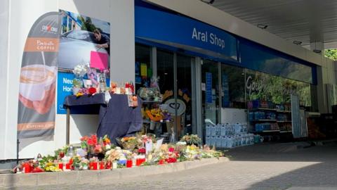 Flowers are placed in front of a gas station in Idar-Oberstein, Germany, September 21, 2021, after a 20-year-old gas station attendant who asked a customer to wear a face mask was shot dead last Saturday