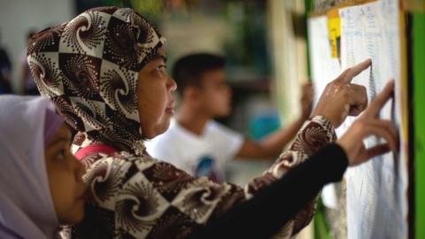 Muslim women look for their names at a voting precinct in Maguindanao, on the southern island of Mindanao on January 21, 2019, the