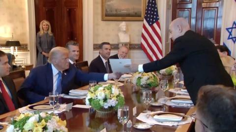 Benjamin Netanyahu hands a piece of paper to Donald Trump
