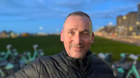 Southern Water customer on Hove seafront wearing a black jacket 