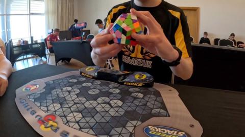 Boy sitting at table holding a megaminx