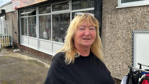 Wendy English the founder of Second Chance Sunderland stands in front of their new store in Hendon. She had shoulder-length blonde hair and smiles at the camera.