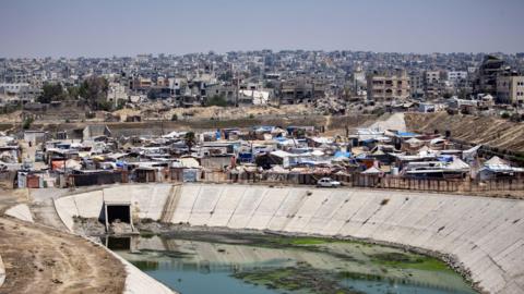 Displaced Palestinians set up their tents next to sewage and a garbage dump on a street in Khan Younis camp in the southern Gaza Strip, 01 August 2024