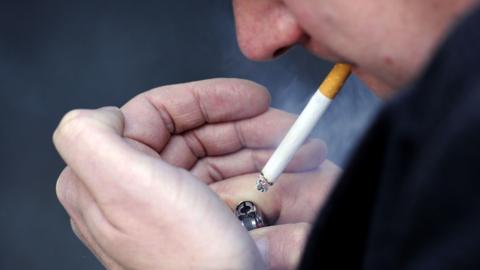 Close up of a man lighting a cigarette using a lighter. 