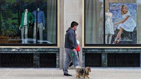 Man in a mask walks by Brooks Brothers store