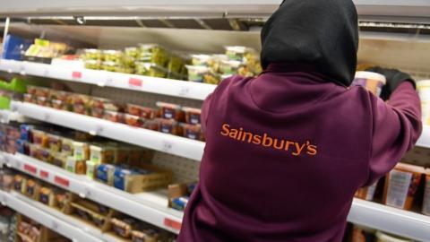 A Sainsbury's worker places products on a shelf